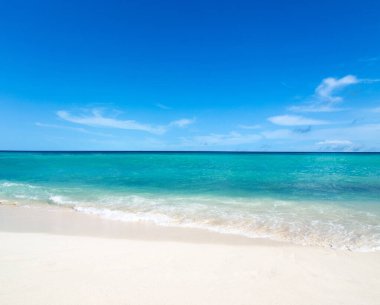 Güzel sahil. Tropik plaj. Tatil ve tatil konsepti. Kum, mavi deniz suyu, turkuaz okyanus, güneş gökyüzü beyaz bulutlar.