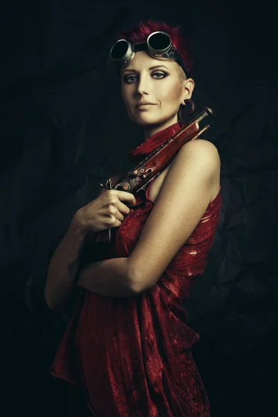 Retrato de uma bela mulher steampunk segurando uma arma sobre fundo grunge . Fotos De Bancos De Imagens