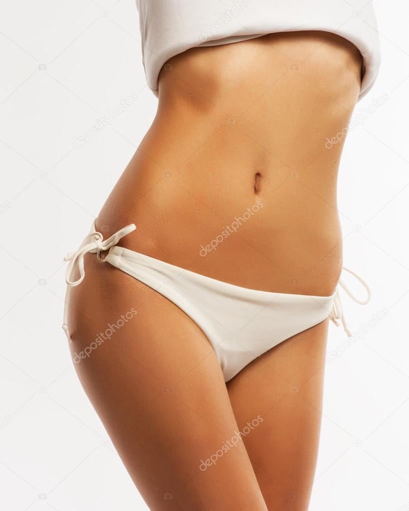 Slim tanned woman's body. Isolated over gray background.