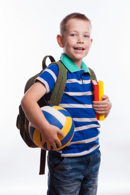 Sırt çantası, top ve beyaz arka plan üzerinde izole kitap ile mutlu okul çocuğu
