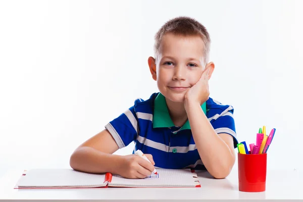 Cute schoolboy is writting isolated on a white background Royalty Free Stock Photos