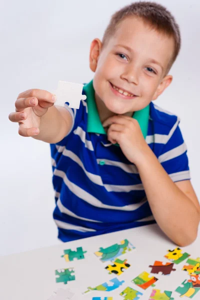 Cute little boy playing puzzles at the table — Stock Photo, Image