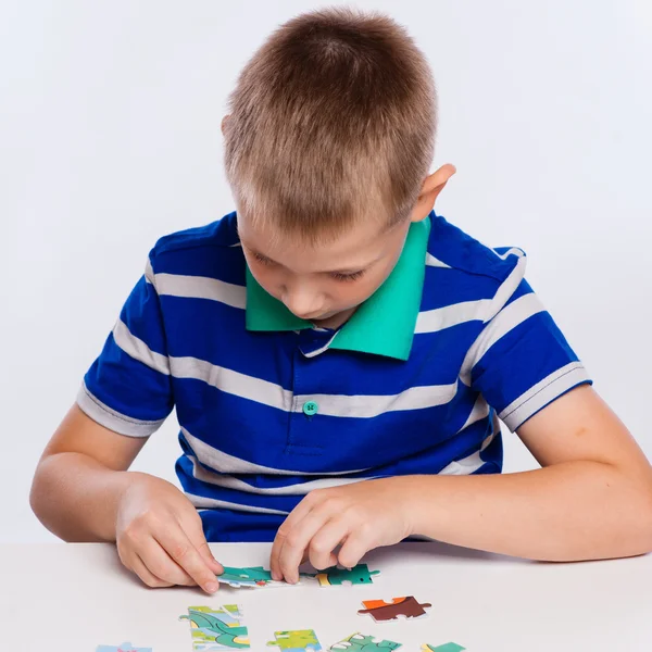 Bonito menino jogando quebra-cabeças na mesa Fotos De Bancos De Imagens