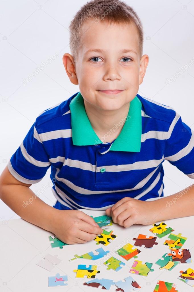 Cute little boy playing puzzles at the table