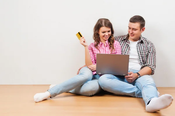 Compras en línea juntos. Hermosa pareja amorosa joven de compras en línea mientras están sentados en el suelo juntos — Foto de Stock