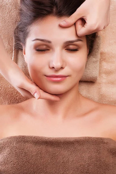 Eautiful joven mujer relajada disfrutar de recibir masaje facial en el salón de spa Fotos de stock libres de derechos