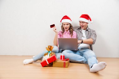 Online Noel alışveriş. Mutlu gülümseyerek çift Internet alışveriş yapmak için kredi kartı ile. Genç çift, laptop ve kredi kartı online satın alma. Noel ve yeni yıl hediye. e-alışveriş