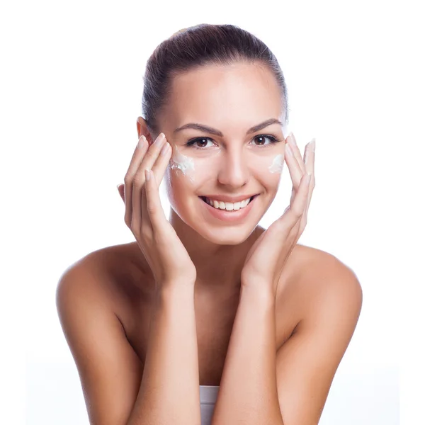 Hermosa modelo aplicando tratamiento de crema cosmética en su cara en blanco —  Fotos de Stock