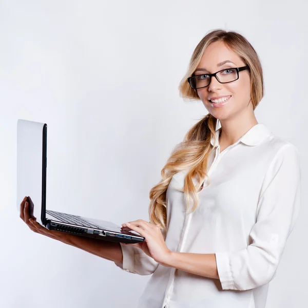 Gelukkig leuke vrouw weergegeven: lege laptop computerscherm over grijze achtergrond. Camera kijken — Stockfoto