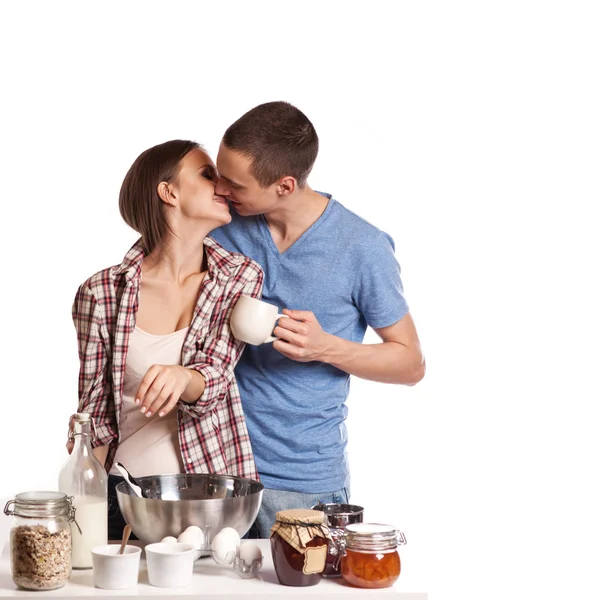 Ласковый мужчина целует свою девушку, пока режет хлеб на завтрак на кухне — стоковое фото