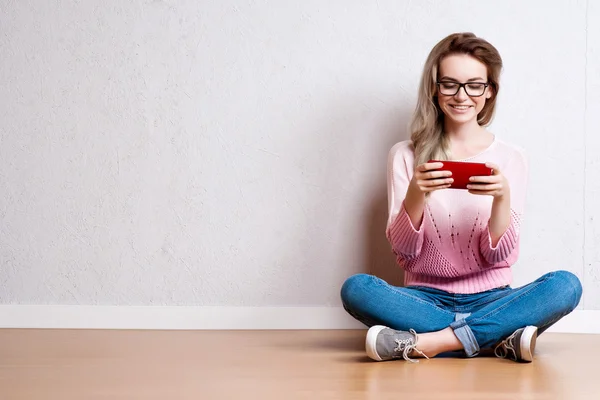 Happy vacker kvinna sitter på golvet och använder smartphone — Stockfoto