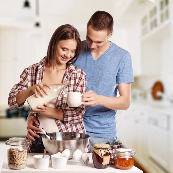 Heureux jeune couple s'amuser dans la cuisine moderne en bois à l'intérieur tout en préparant des aliments frais — Photo