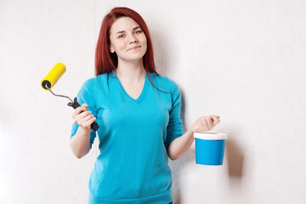 Belle jeune femme en vêtements causals appréciant le résultat du travail qu'elle a fait peindre un mur . — Photo