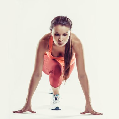 Kadın atlet gri arka plan üzerinde çalışmaya hazır uygun. Bir sprint için hazırlama kadın fitness modeli