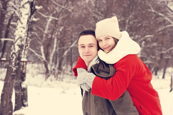 Abrazando pareja mirando a la cámara con sonrisas en el parque de invierno — Foto de Stock