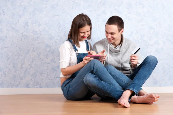 Compras en línea juntos. Hermosa pareja amorosa joven de compras en línea mientras están sentados en el suelo juntos — Foto de Stock