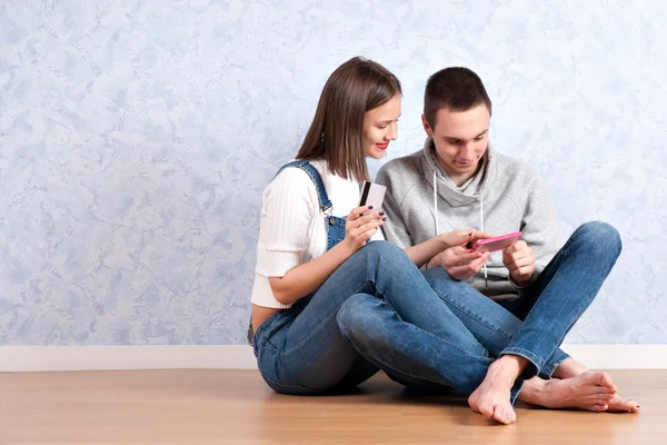 Shopping online together. Beautiful young loving couple shopping online while sitting on the floor together — Stock Photo, Image