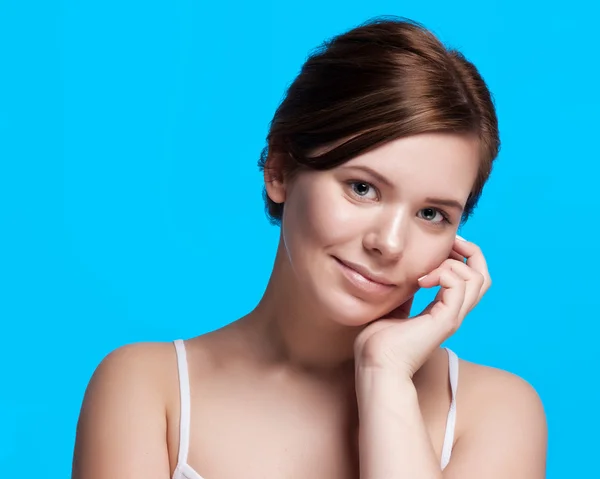 Beautiful face of young adult woman with clean fresh skin - isolated on blue — Stock Photo, Image