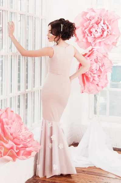 Menina sexy bonita em um vestido longo com uma enorme flores rosa . — Fotografia de Stock