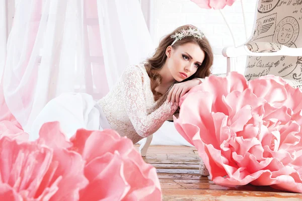 Schöne sexy Mädchen in einem langen Kleid mit einem riesigen rosa Blumen sitzen — Stockfoto