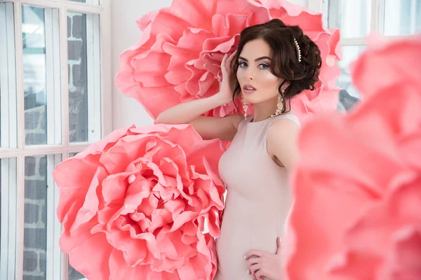 Bella ragazza sexy in un abito lungo con un enorme fiori rosa seduti vicino alla finestra — Foto Stock