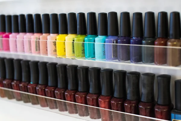 Set of different nail varnishes on shelves in cosmetic store — Stock Photo, Image