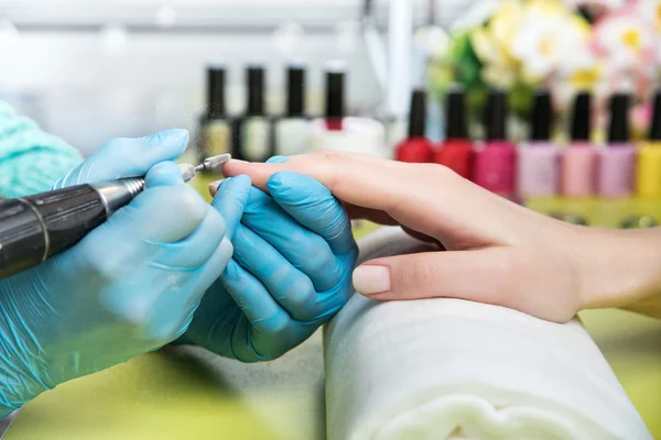 Nahaufnahme einer Frau in einem Nagelstudio, die von einer Kosmetikerin mit Nagelfeile eine Maniküre erhält. Frau bekommt Nagelmaniküre. Kosmetikerin feilt Nägel an Kundin — Stockfoto