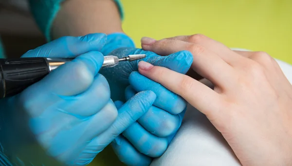 Nahaufnahme einer Frau in einem Nagelstudio, die von einer Kosmetikerin mit Nagelfeile eine Maniküre erhält. Frau bekommt Nagelmaniküre. Kosmetikerin feilt Nägel an Kundin — Stockfoto