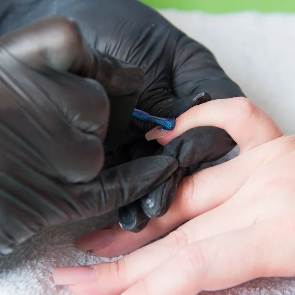 Nahaufnahme einer Frau in einem Nagelstudio, die von einer Kosmetikerin mit Nagelfeile eine Maniküre erhält. Frau bekommt Nagelmaniküre. Kosmetikerin feilt Nägel an Kundin — Stockfoto