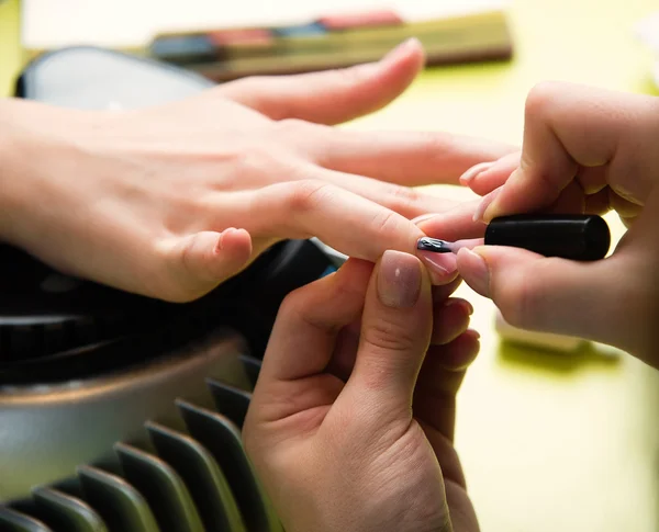 Detailní záběr ženy v nehtový salon příjem manikúru od kadeřnice s pilník. Žena stále nehty manikúra. Kosmetička soubor hřebíky k zákazníkovi Royalty Free Stock Fotografie