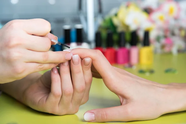 Closeup shot of a woman in a nail salon receiving a manicure by a beautician with nail file. Woman getting nail manicure. Beautician file nails to a customer Stock Picture