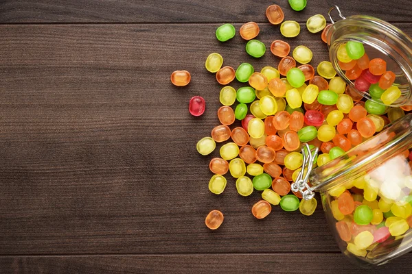 Overturned glass jar full of colorful sweets — Stock Photo, Image