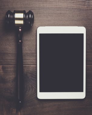 Yargıç tokmak ve tablet bilgisayar üzerinde kahverengi ahşap backgroundjudge