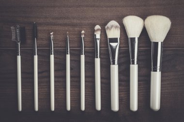 ahşap masa üzerinde beyaz makyaj fırçaları