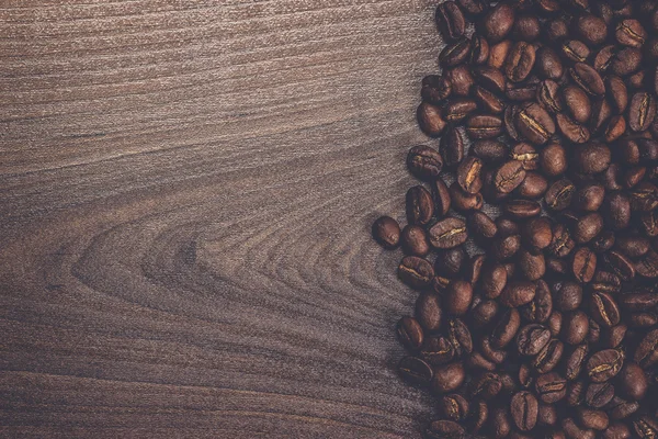 Grãos de café em fundo de madeira marrom — Fotografia de Stock