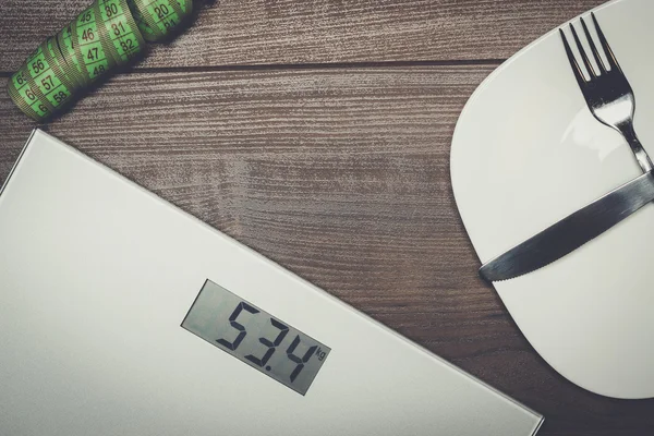 Dieting concept with scales on wooden floor — Stock Photo, Image