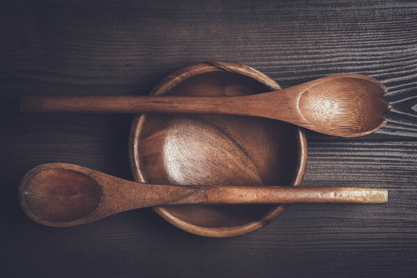 empty salad bowl and two spoons on wooden table