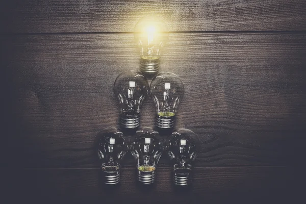 Glowing bulb leadership concept on wooden background — Stock Photo, Image