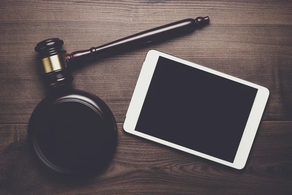 Yargıç tokmak ve tablet bilgisayar üzerinde kahverengi ahşap backgroundjudge