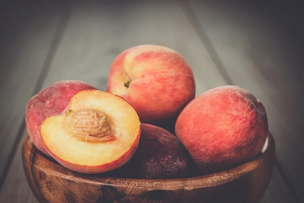 Ciotola di legno alcune pesche fresche sul tavolo — Foto Stock