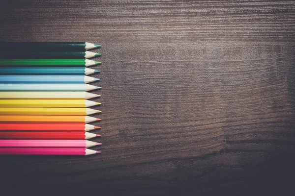Kahverengi masa arka plan üzerinde renkli kalemler — Stok fotoğraf