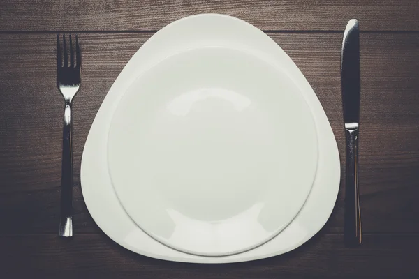 Placas blancas con cuchillo y tenedor sobre mesa de madera —  Fotos de Stock