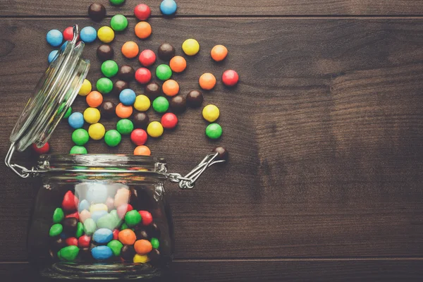 Pot en verre renversé plein de bonbons colorés — Photo