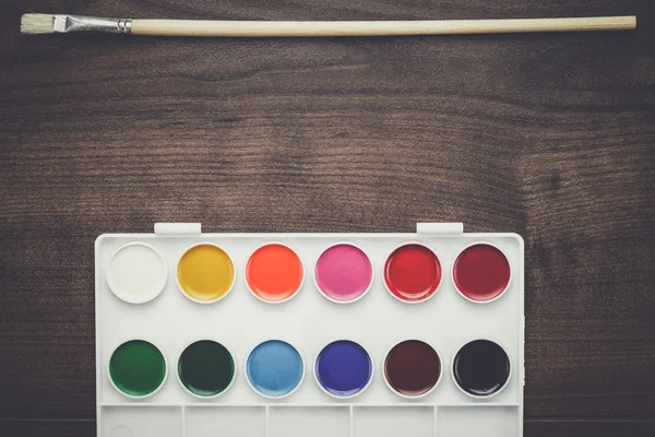 Box of paints and a brush on the table — Stock Photo, Image