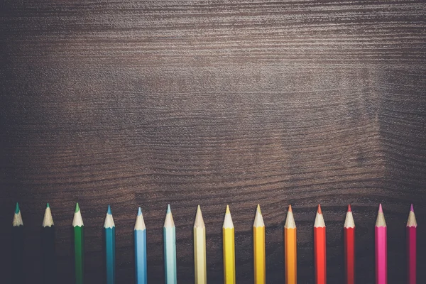 Разноцветные карандаши на фоне коричневого деревянного стола — стоковое фото
