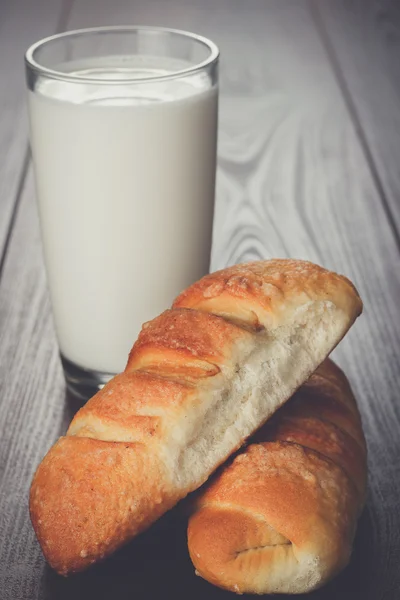 Sklenici mléka a čerstvé housky na stůl — Stock fotografie