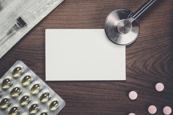 Cuaderno en blanco statoscopio y pastillas en la mesa de madera —  Fotos de Stock