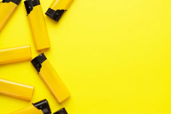 Plastic lighters on yellow background — Stock Photo, Image