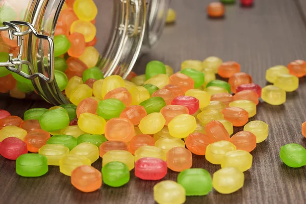 Omvergeworpen in glazen pot vol met kleurrijke snoep — Stockfoto