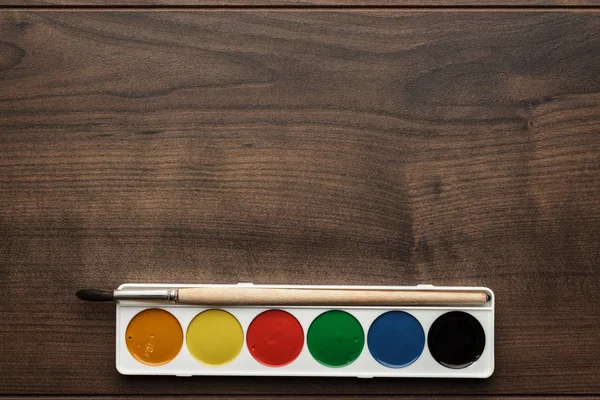 Коробка красок и кисть на столе — стоковое фото